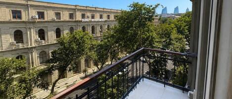 A balcony with a view of a historic building with arched windows and a sign that reads 'Doniz Akaleem Yasa'.