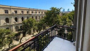 A balcony with a view of a historic building with arched windows and a sign that reads 'Doniz Akaleem Yasa'.