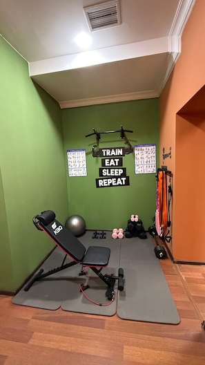 A home gym with exercise equipment, a pull-up bar, and motivational posters on the wall.