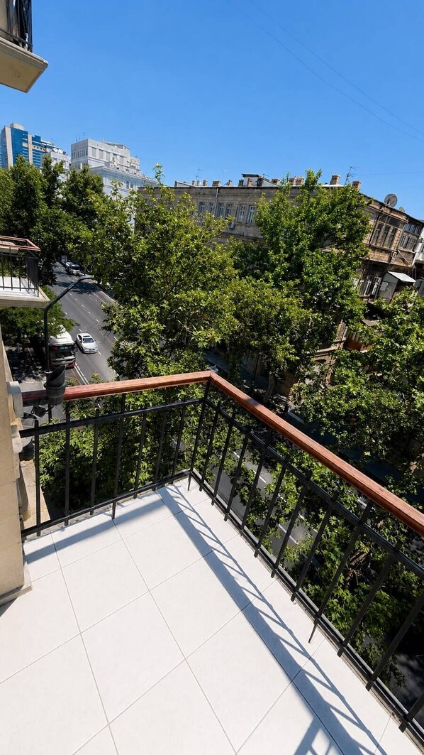 A balcony with a metal railing overlooking a street with cars and buildings.