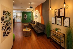 Un moderno vestíbulo de hotel con un sofá, mesas redondas y una decoración mural inspiradora.
