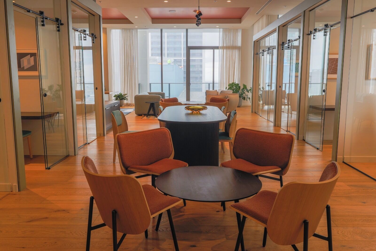 A modern conference room with a round table, six chairs, and glass walls.