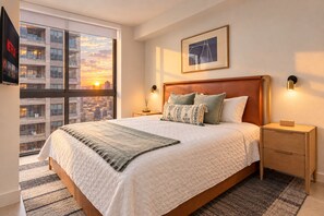 A hotel room with a large bed, a city view, a framed artwork on the wall, and a bedside table with a lamp. - Miami Urban Retreat (Miami)