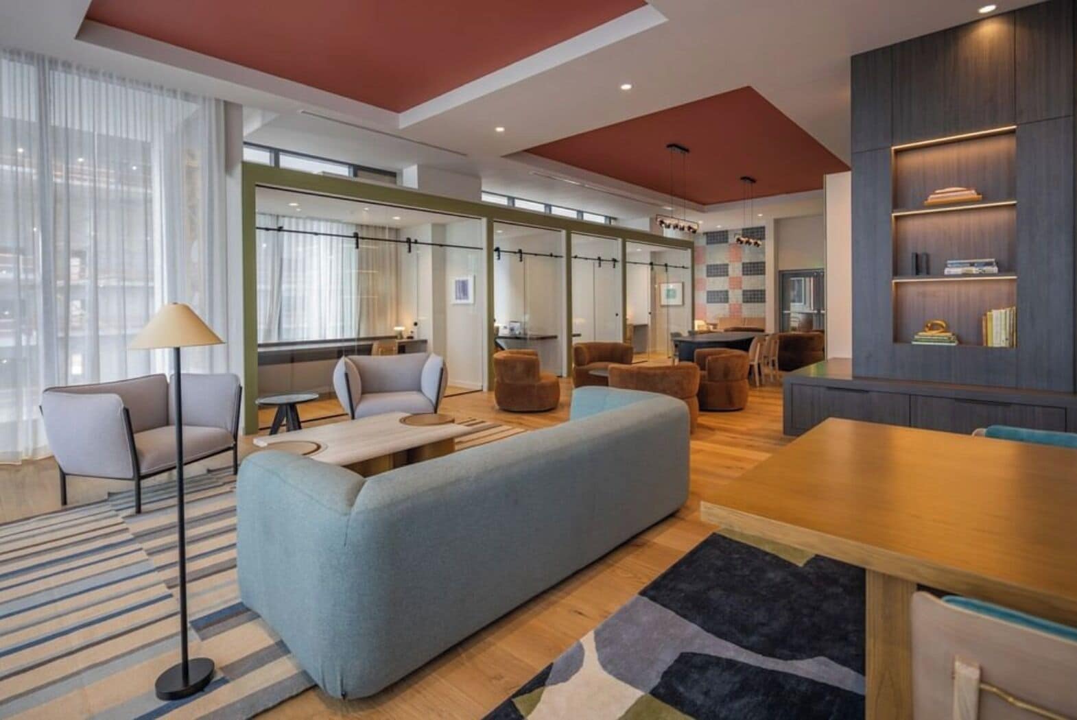 A modern interior with a sofa, chairs, a dining table, and a bookshelf.