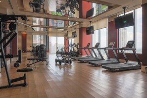 Un gimnasio con cintas de correr, máquinas de pesas y bicicletas estáticas.