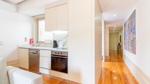 A modern kitchen with a built-in oven, a coffee machine, and a window above the sink. - Cedofeita Boutique Flat w/ AC by LovelyStay (Porto)