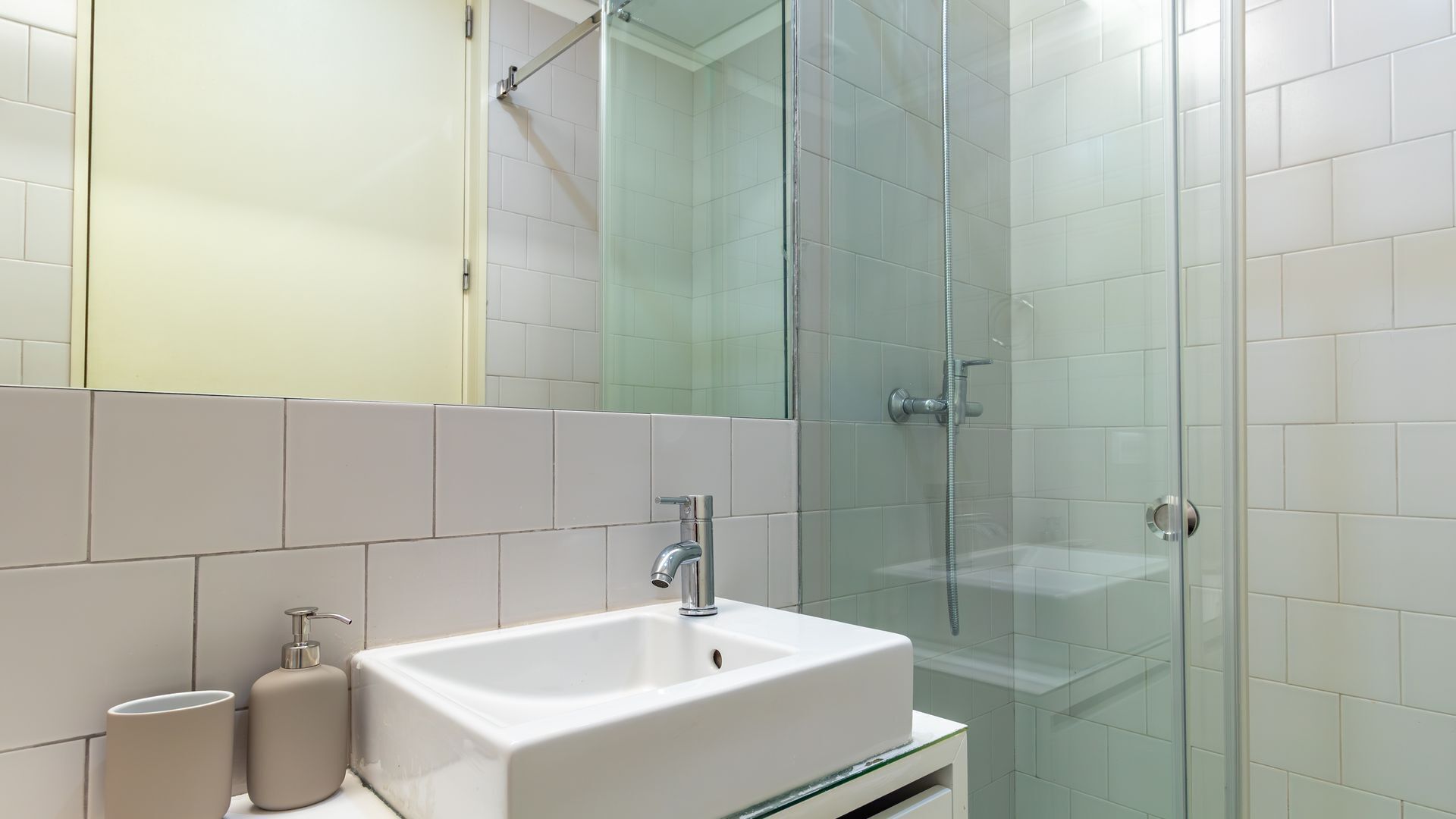 A bathroom with a white sink, a mirror, and a glass shower enclosure.