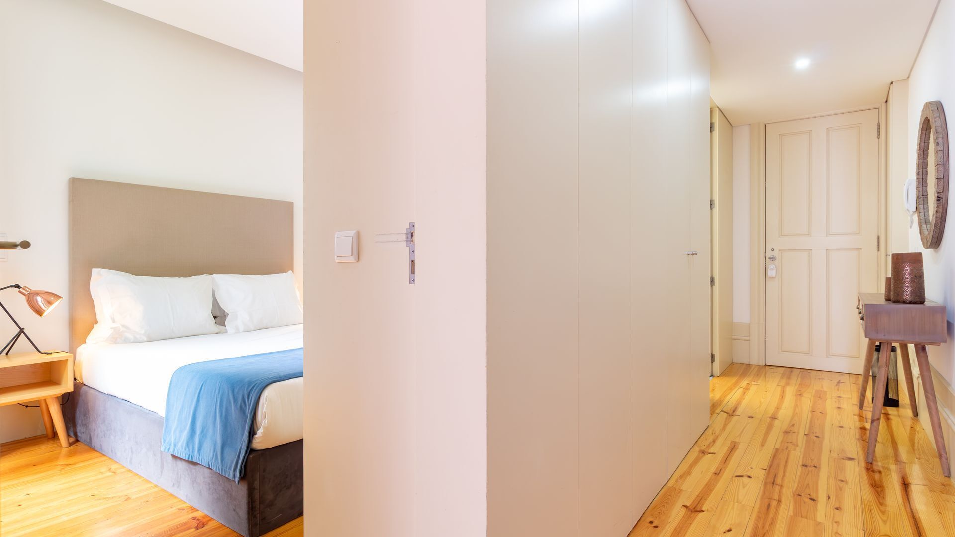 A bedroom with a bed, bedside lamp, and a wooden nightstand.