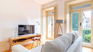 A living room with a television, a sofa, a small table, and a floor lamp. - Cedofeita Boutique Flat w/ AC by LovelyStay (Porto)
