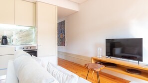 A modern living room with a sofa, a coffee maker, a television, and a wooden side table. - Cedofeita Boutique Flat w/ AC by LovelyStay (Porto)
