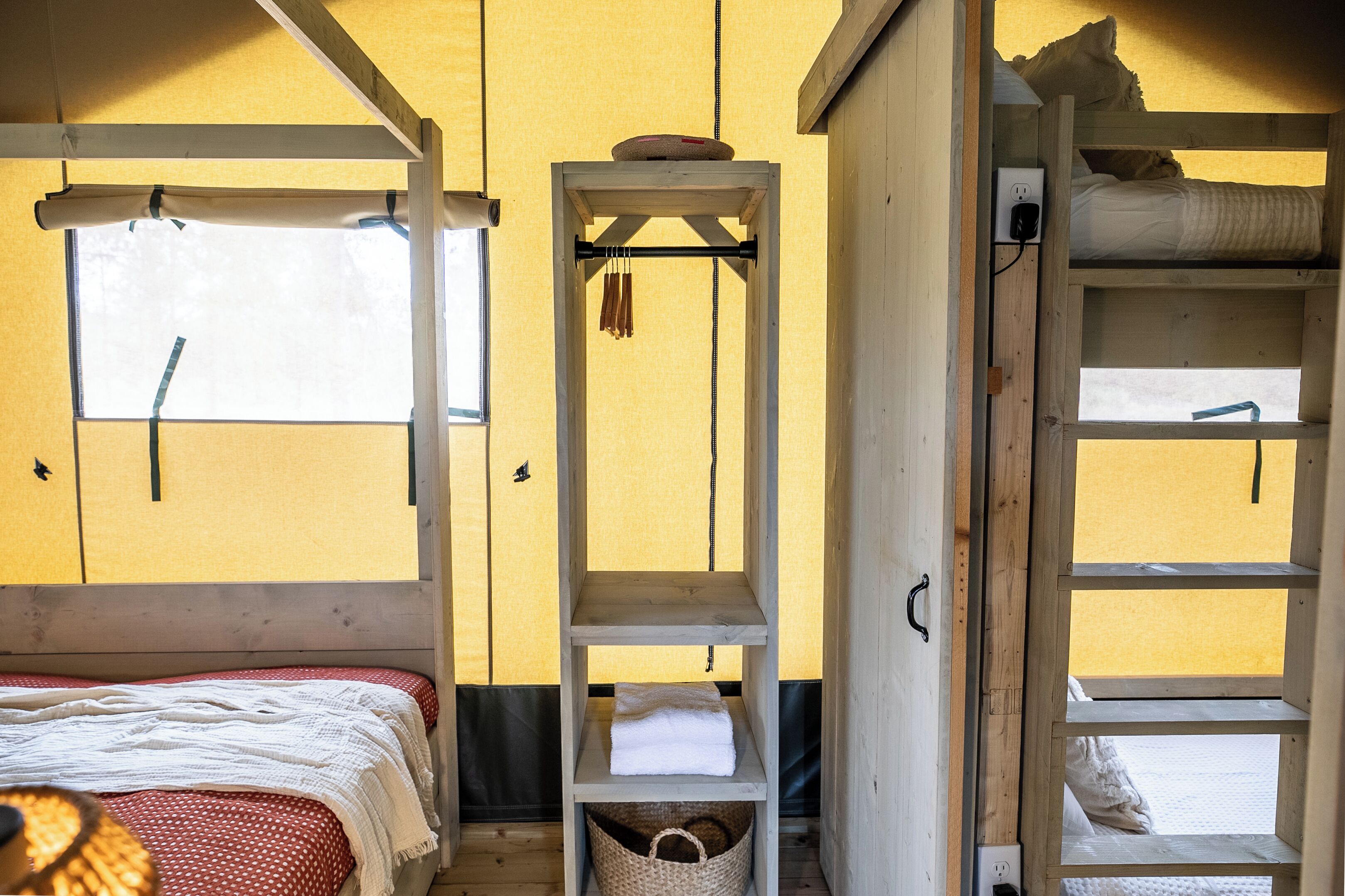 A room with a bunk bed, a shelf with towels, and a window.