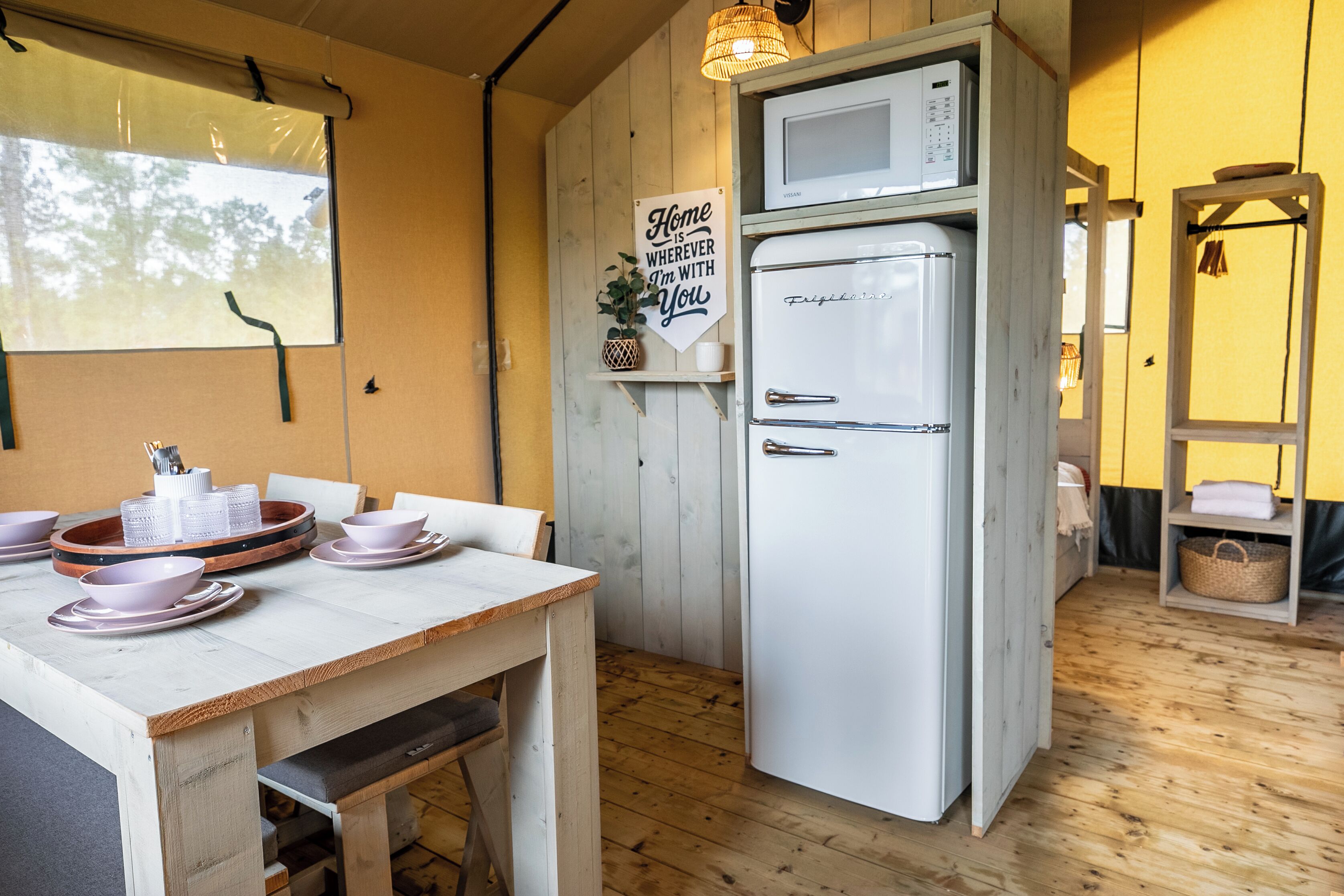 A kitchen with a white refrigerator, wooden cabinets, and a dining table with pink dishes.