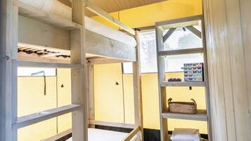 A bunk bed with a shelf unit beside it, containing a basket and a box of butterfly stickers.