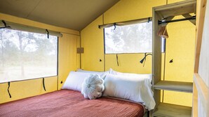 Una cama individual con una colcha estampada en rojo y blanco, dos almohadas blancas y un cabecero de madera.