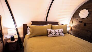 A cozy room with a bed, a lamp, and a circular mirror on the wall.