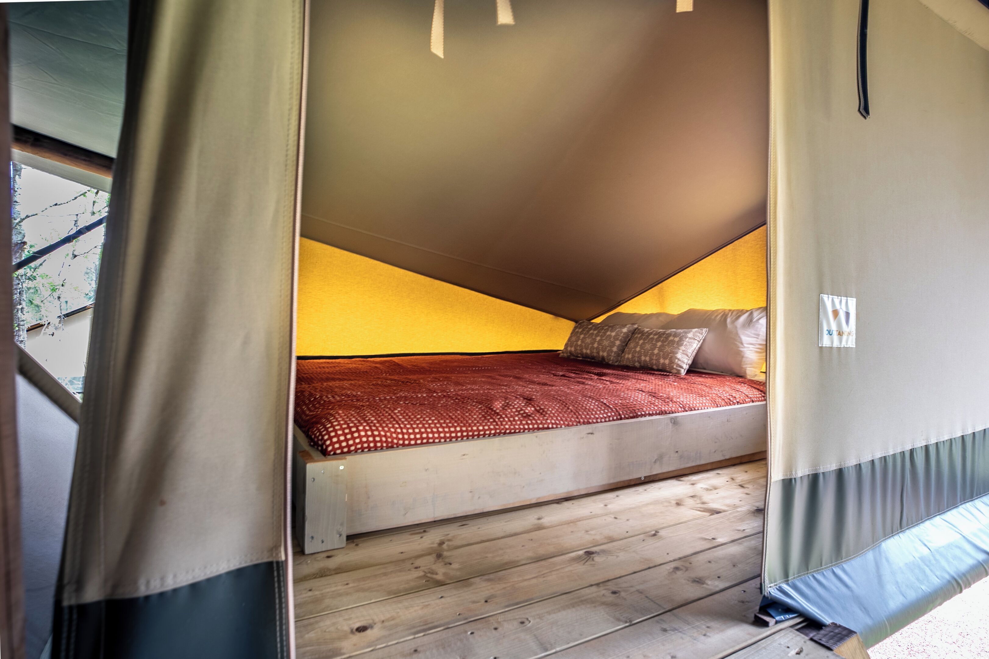 A compact bedroom with a sloped ceiling, a single bed, and a wooden floor.