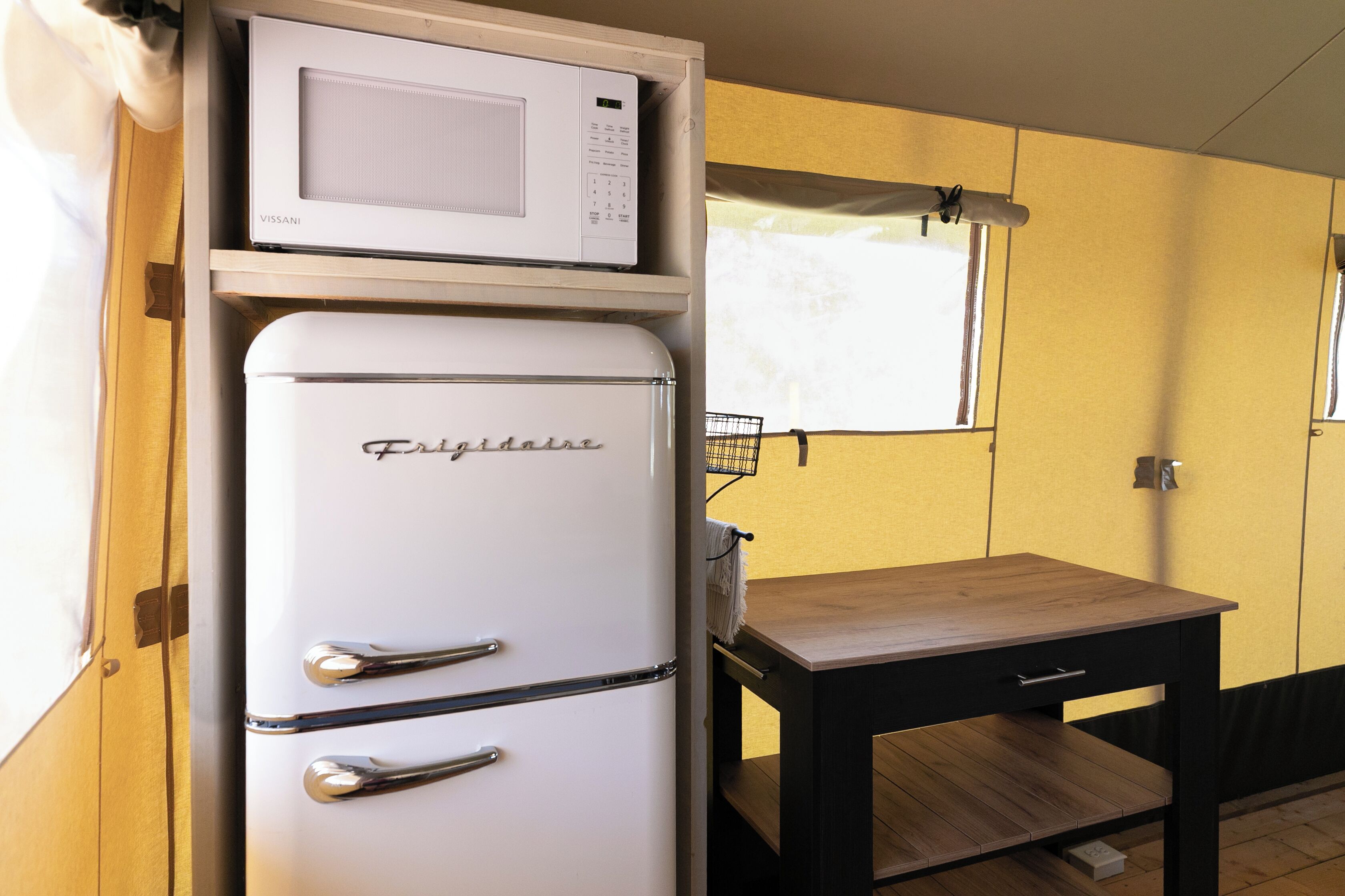 Una cucina compatta con un frigorifero bianco, un forno a microonde e un piccolo tavolo di legno.