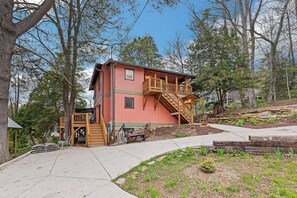 A two-story building with a wooden staircase leading to a balcony, surrounded by trees.