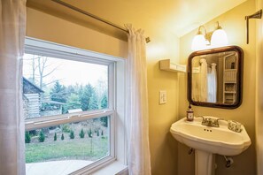 A bathroom with a window, a sink, and a mirror.