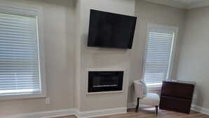 Een slaapkamer met een bed, een flatscreen televisie, een open haard en een dressoir.