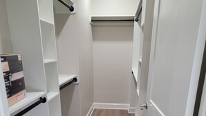 Een inloopkast met witte schapunits, een houten vloer, en een deur aan de rechterkant.