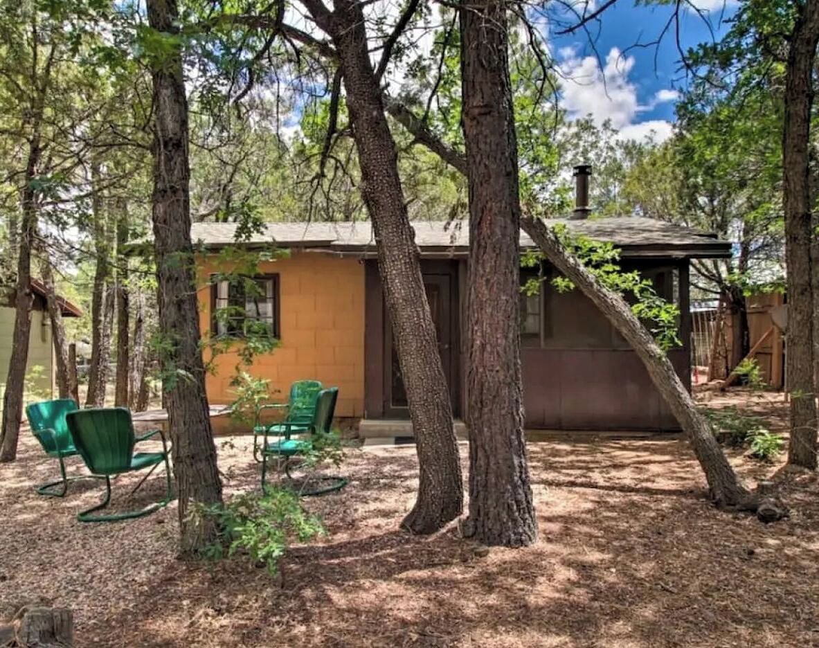 A rustic cabin with a small porch, surrounded by trees.