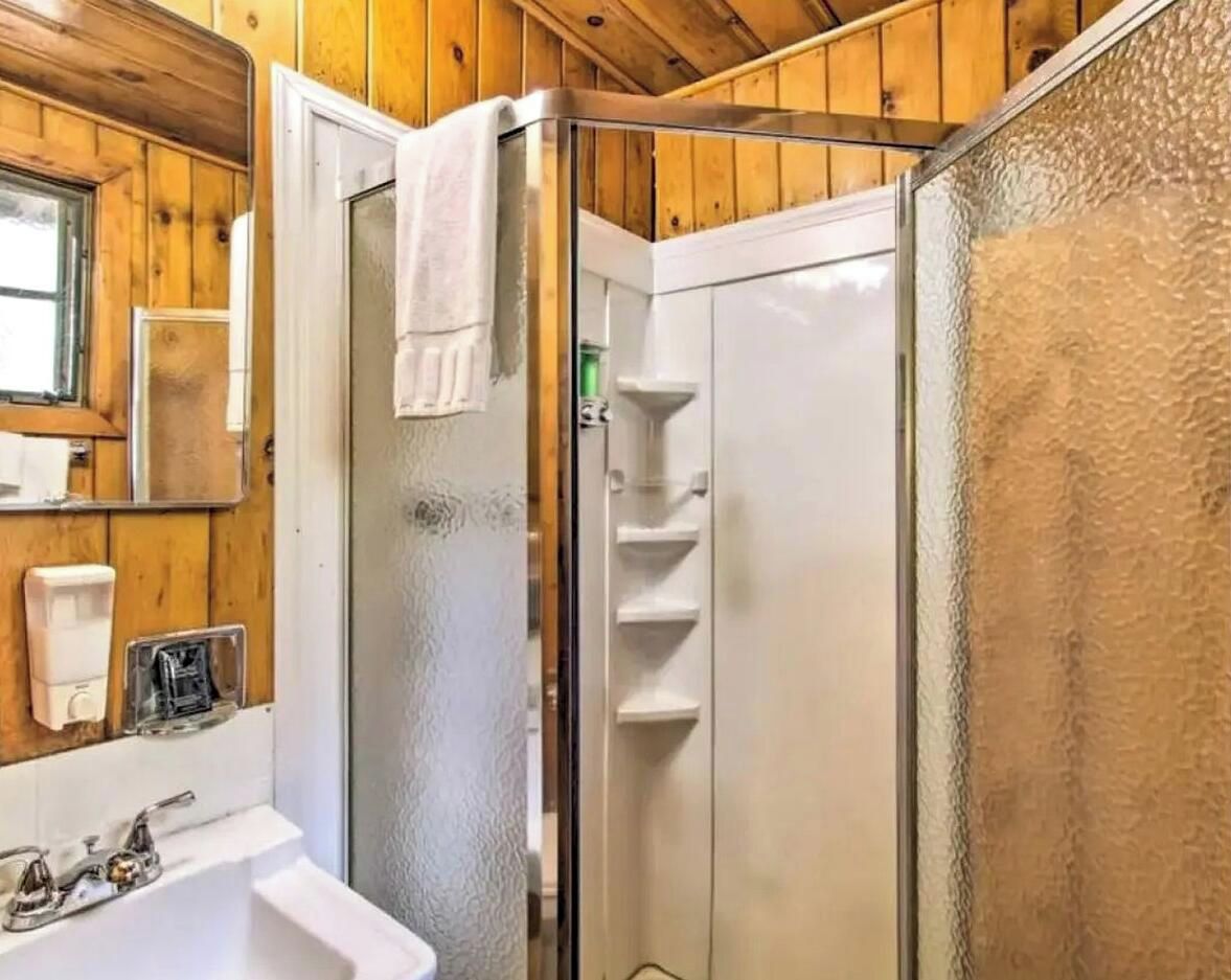 Une salle de bain avec une douche à parois de verre, un lavabo blanc et un miroir.