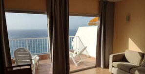 Een balkon met uitzicht op zee, een witte stoel en een bank.