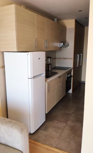 A kitchen with light wooden cabinets, a white refrigerator, and a stove. - Excellent apartment with splendid ocean views (Puerto de la Cruz)