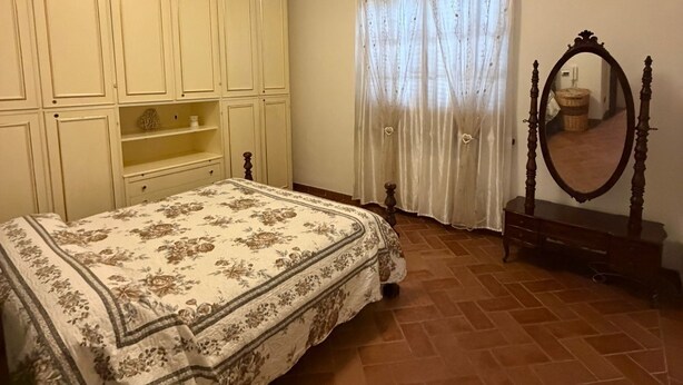 A bedroom with a bed, wardrobe, mirror, and curtains. - Casa Elena and Daniele, an elegant apartment 3 kilometers from the sea (Viareggio)