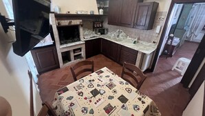 A compact kitchen with dark wooden cabinets, a marble countertop, and a dining table with a patterned tablecloth. - Casa Elena and Daniele, an elegant apartment 3 kilometers from the sea (Viareggio)