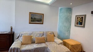 A room with a sofa bed, a small table, and two framed pictures on the walls. - Casa Elena and Daniele, an elegant apartment 3 kilometers from the sea (Viareggio)