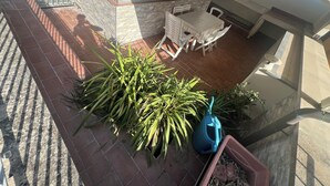 A patio area with a table and chairs, a potted plant, and a blue watering can. - Casa Elena and Daniele, an elegant apartment 3 kilometers from the sea (Viareggio)