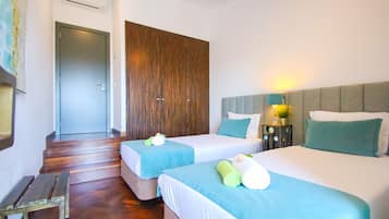 A hotel room with two beds, a wooden bench, a wardrobe, and a staircase.