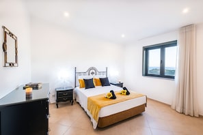 Ein Schlafzimmer mit Bett, Nachttischen, einem Schminktisch, einem Spiegel und einem Fenster mit Aussicht.