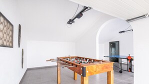 Una stanza con un tavolo da calcio, un tavolo da ping pong e una porta che dà su un'altra stanza.