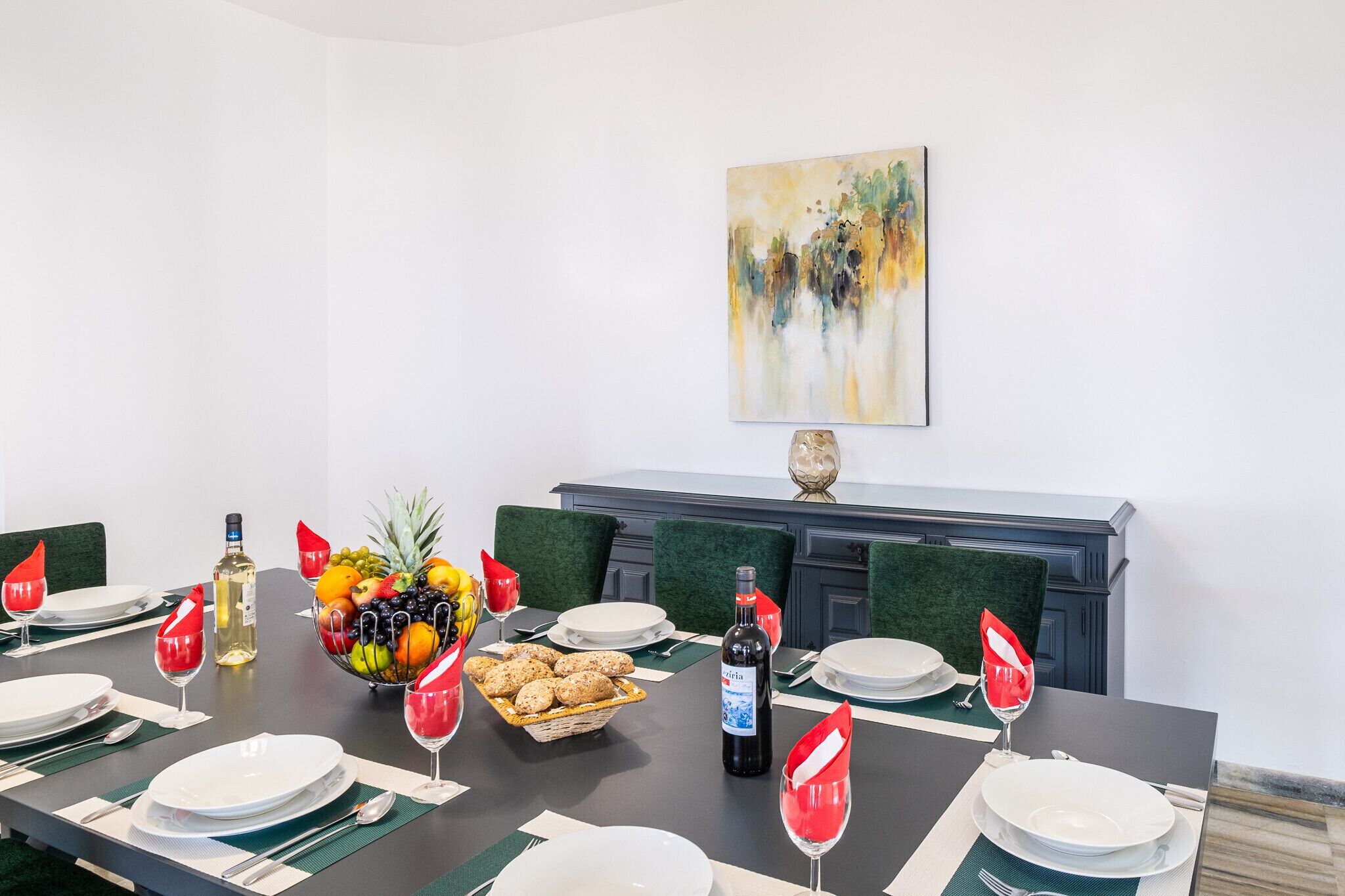 A dining table set for a meal with plates, glasses, and a fruit bowl.