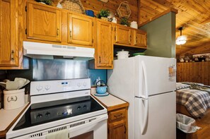 Une cuisine avec des meubles de rangement en bois, une cuisinière, un réfrigérateur et une bouilloire.