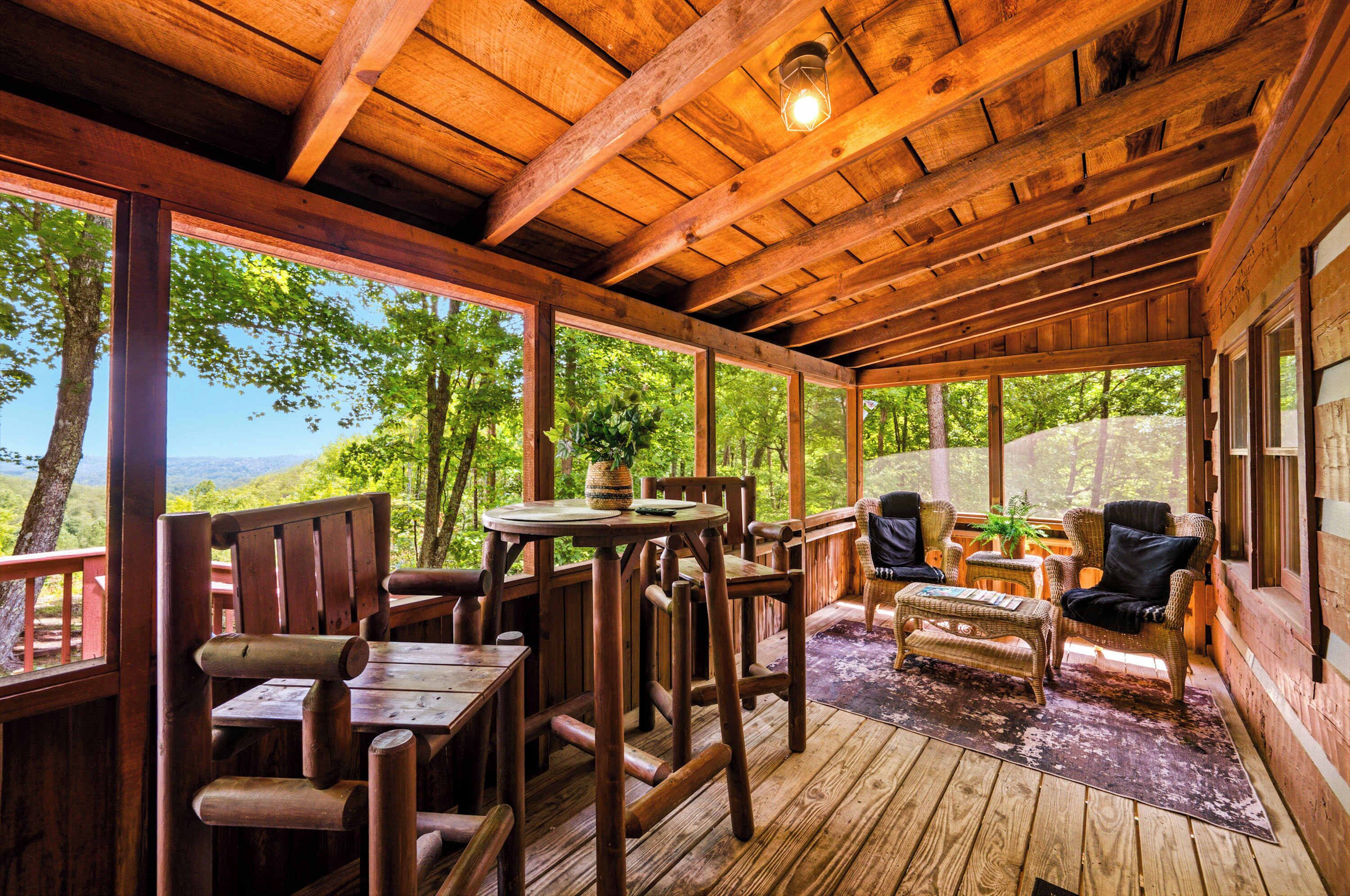 A wooden deck with a table and chairs, overlooking a forested area.