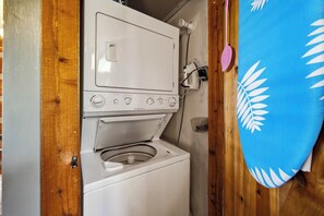 Ein kleiner Waschraum mit Waschmaschine und Trockner, Holzwänden und einem blauen Handtuch, das rechts hängt.