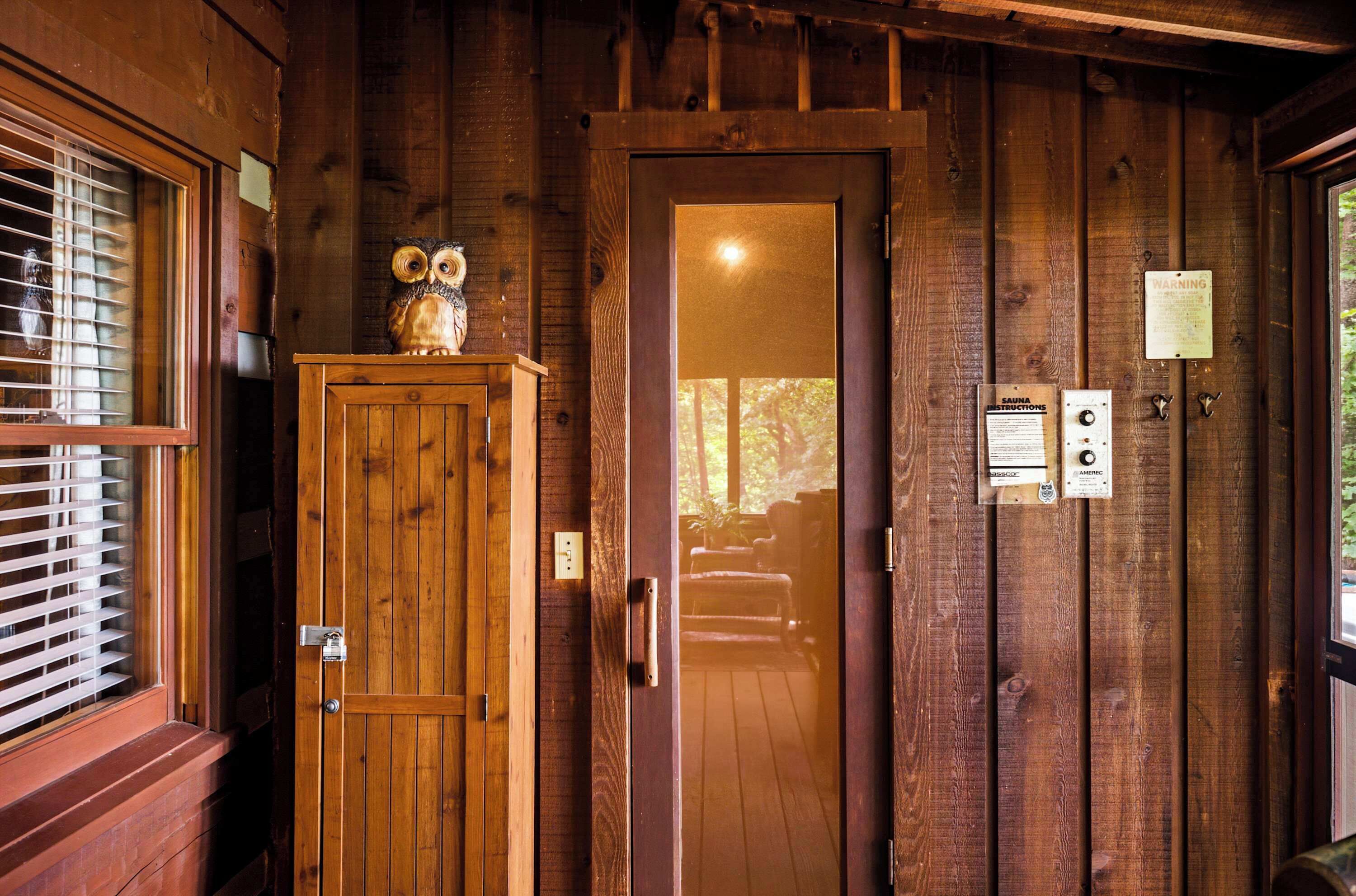 A wooden door with a glass panel, a wooden cabinet with an owl decoration, and a wall-mounted control panel with instructions.