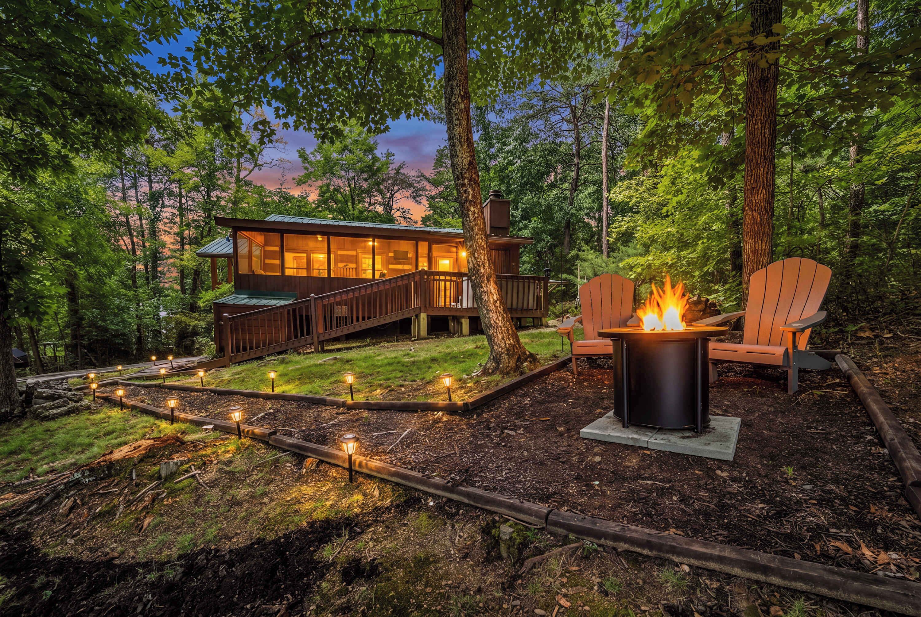 A cabin with a deck, a fire pit, and outdoor lighting.