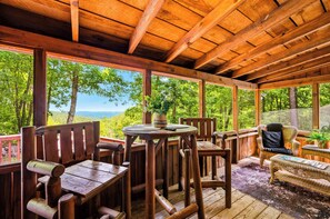 A wooden deck with a table and chairs, overlooking a forested landscape. - View! Hot Tub-Sauna-Fire Pit-Fireplace-Honeymoon (Sevierville)