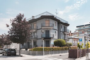 Un edificio residenziale a più piani con balconi, un segnale di parcheggio e un attraversamento pedonale.