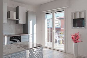 Une cuisine moderne avec des meubles blancs, un plan de travail en marbre et un coin repas comprenant une table et des chaises blanches.