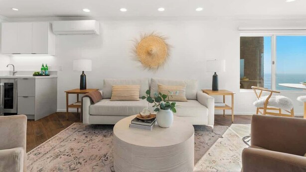 A modern living room with a sofa, coffee table, and a view of the ocean. - Oceanfront, AC, Fully Remodeled Unit (Solana Beach)