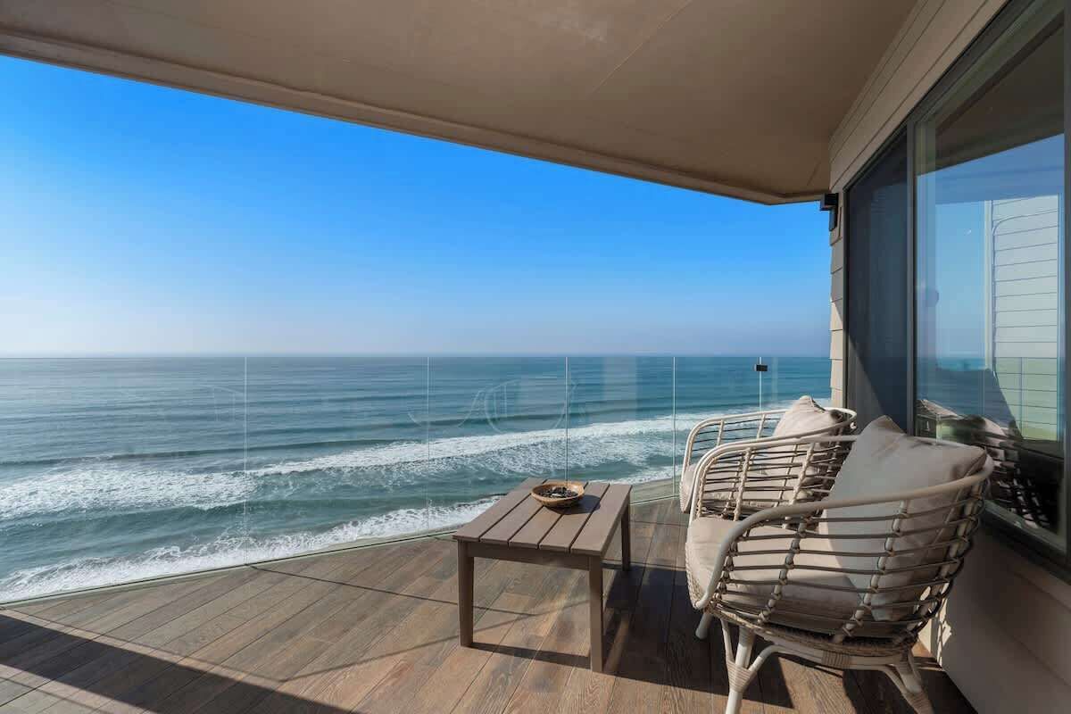Een balkon met uitzicht op de oceaan, een tafel en twee stoelen.