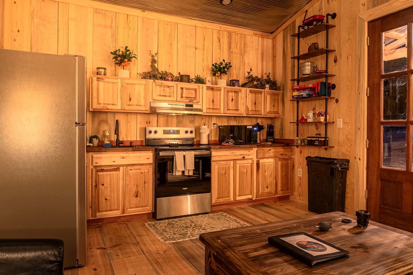 A kitchen with wooden cabinets, a stainless steel refrigerator, a stove, and a microwave.