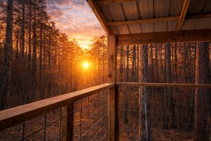 A wooden cabin with a balcony overlooking a forest at sunset. - Cabin Retreat with Fire Pit & Scenic Ridge Views in Caddo Gap, Arkansas (Caddo Gap)