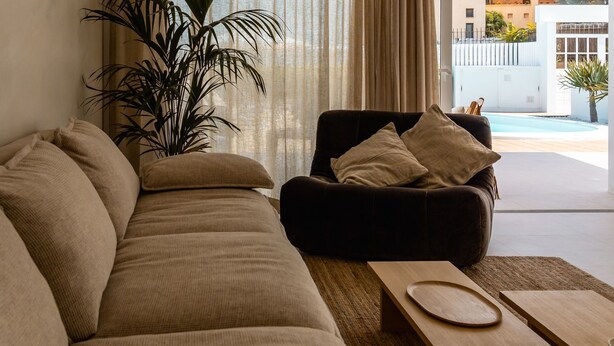 A modern living room with a large sofa, a smaller armchair, and a wooden coffee table. - Villa Playa Vista Lobos (Corralejo)